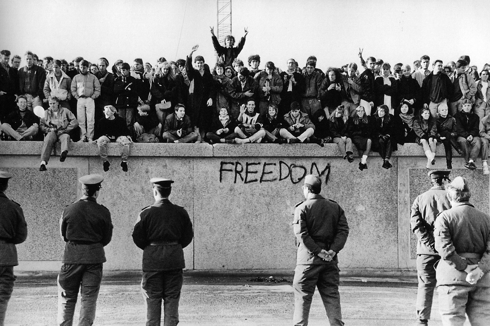 Študenti z NDR sedia na Berlínskom múre pri Brandenburskej bráne. 1989. University of Minnesota Institute of Advanced Studies